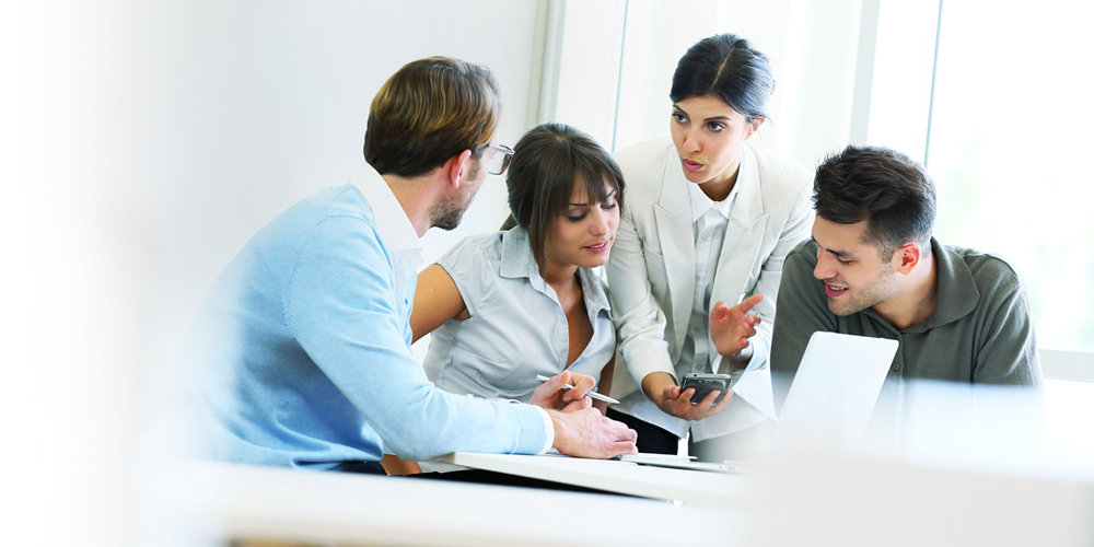 SDL smartQuery - Four people gathered around a laptop